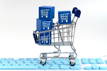 A creative e-commerce visual featuring a tiny trolley transporting a blue shopping box, set atop a vibrant blue keyboard representing digital shopping