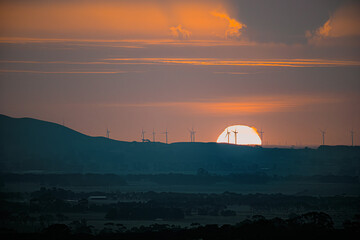 Obraz premium Sunset over wind turbines with farm land in the foreground, Camperdown, Victoria, Australia