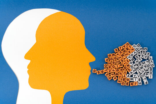 Two intersecting paper-cut heads, white and yellow, with contrasting letter patterns in the brain area. A cloud of mixed letters flows from the white mouth, symbolizing the contrasting moods  