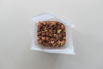 "Top-down shot of chocolate-flavored popcorn in a white bag, set against a white background."