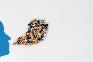 A paper-cut human head with a mix of letters in the brain area, as streams of mixed letters flow...