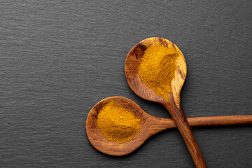Wooden Spoons with Turmeric Powder on Slate Background – Natural Cooking Ingredients