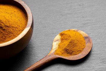 Wooden Spoons with Turmeric Powder on Slate Background – Natural Cooking Ingredients
