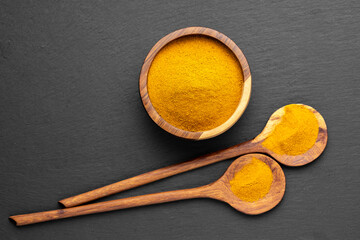 Wooden Spoons with Turmeric Powder on Slate Background – Natural Cooking Ingredients