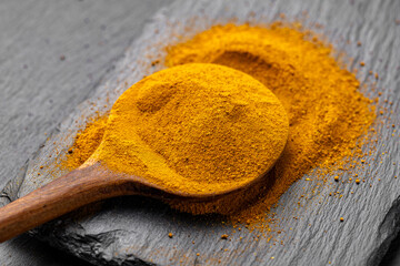 Wooden Spoons with Turmeric Powder on Slate Background – Natural Cooking Ingredients