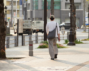 春の夕方の都市の街で歩く一人の若者の姿
