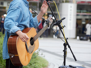 日本の駅前広場でギターを演奏する若者の姿
