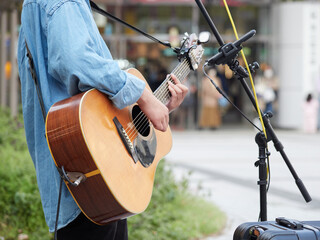 日本の駅前広場でギターを演奏する若者の姿