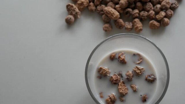 Glass of horchata with tiger nuts on white table, refreshing summer drink scene