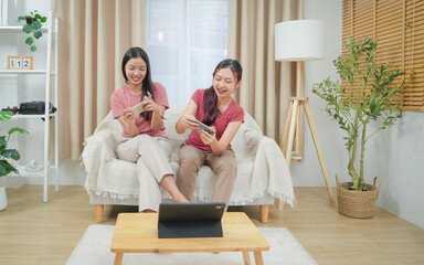 Two happiness asian smiling young woman gamer using smart phone or mobile phone and playing games...