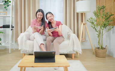 Two happiness asian smiling young woman gamer using smart phone or mobile phone and playing games...