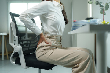Businesswoman suffering from back pain while working at office desk