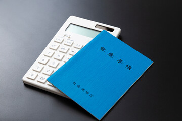 黒背景に年金手帳と電卓