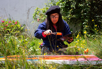 Female painter picking up orange paint with a palette knife in a garden