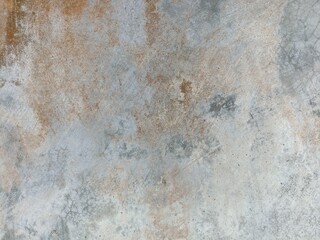 Weathered Concrete Wall with Faded Texture. Close-up of an old concrete wall with faded orange and gray patches, showing natural wear, cracks, and gritty surface texture