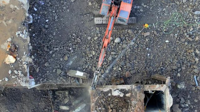 Excavator with hydraulic hammer dismantling a building at a construction site
