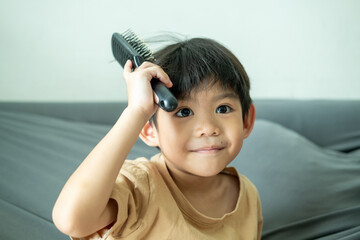 Asian boy using a comb to comb his hair.