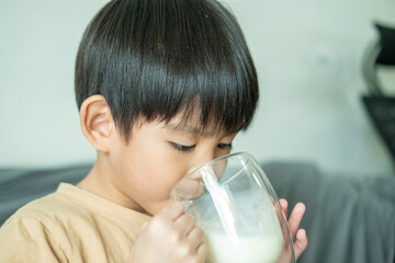 Asian boy is drinking a glass of milk.