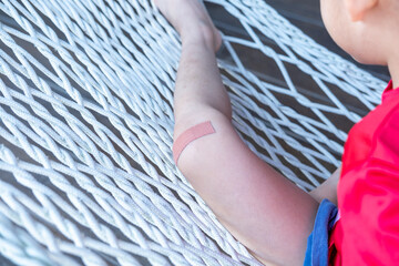 Asian boy sitting on a net with wound dressing plaster.