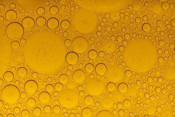 Macro abstract image of golden oil bubbles suspended in liquid, forming overlapping circular...