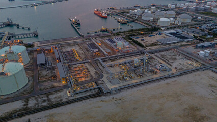 LNG tanker docked at an offshore terminal with multiple pipelines, storage tanks, and an industrial...