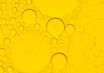 Macro abstract image of golden oil bubbles suspended in liquid, forming overlapping circular...
