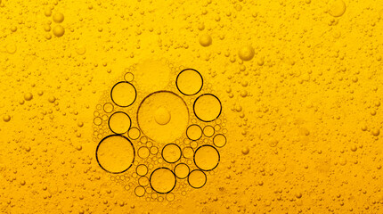 Macro abstract image of golden oil bubbles suspended in liquid, forming overlapping circular...