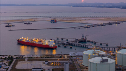 Aerial view of an LNG tanker docked at an offshore terminal with multiple pipelines, storage tanks,...