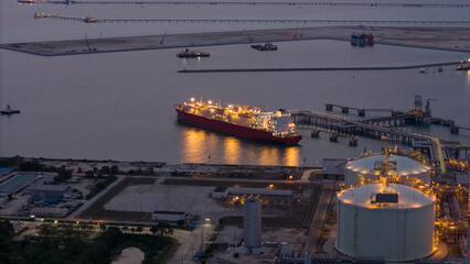 Aerial view of an LNG tanker docked at an offshore terminal with multiple pipelines, storage tanks,...