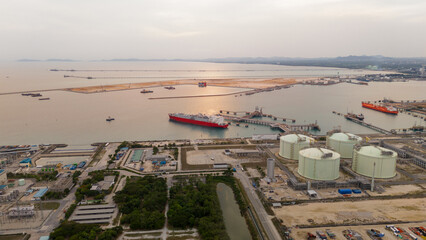 Aerial view of an LNG tanker docked at an offshore terminal with multiple pipelines, storage tanks,...