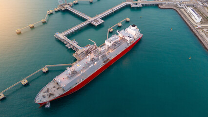 Aerial view of an LNG tanker docked at an offshore terminal with multiple pipelines, storage tanks,...