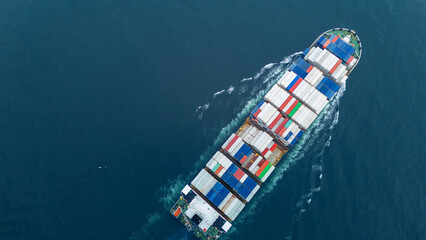Aerial view of a cargo container ship sailing across the open sea, stacked high with colorful...