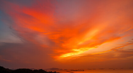 Vibrant fiery sunset over the ocean with silhouettes of cargo ships on the horizon, painting the...