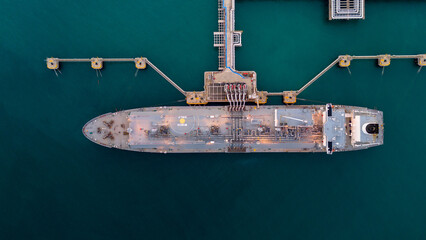 Aerial view of an LNG tanker docked at an offshore terminal with multiple pipelines, storage tanks,...