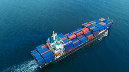 Aerial view of a cargo container ship sailing across the open sea, stacked high with colorful...