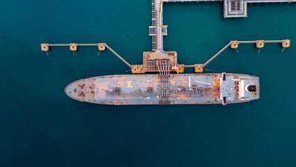 Aerial view of an LNG tanker docked at an offshore terminal with multiple pipelines, storage tanks,...