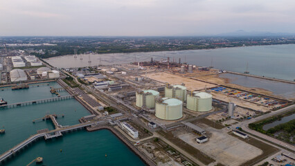 LNG storage tanks and terminal facility at dusk, showcasing large cylindrical containers, offshore...