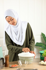 Woman in Hijab  Drains Lettuce from the Water in a Salad Spinner
