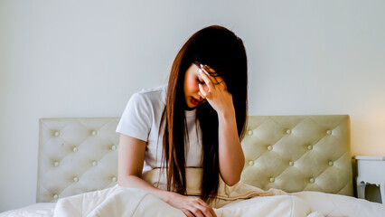 Young asian female having depression sitting alone in bedroom corner. woman headache unhappy emotion. young anxiety despairing mental health problems, Migraines, lack of sleep and depression