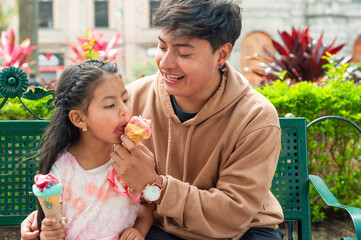 Obraz premium Brother and sister sharing ice cream cones in a park
