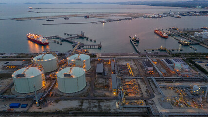 Aerial view of an LNG tanker docked at an offshore terminal with multiple pipelines, storage tanks, and an industrial complex. Captures global energy logistics
