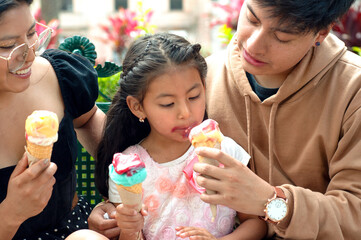 Happy family eating ice cream cones outdoors in summer
