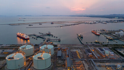 Aerial view of an LNG tanker docked at an offshore terminal with multiple pipelines, storage tanks, and an industrial complex. Captures global energy logistics