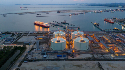 Aerial view of an LNG tanker docked at an offshore terminal with multiple pipelines, storage tanks, and an industrial complex. Captures global energy logistics