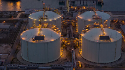 LNG storage tanks and terminal facility at dusk, showcasing large cylindrical containers, offshore piers, and cargo ships. Industrial landscape representing global liquefied natural gas