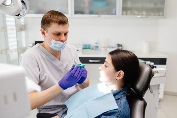 Dentist showing dental mold to young patient in clinic