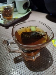 A glass cup of tea with tea bag and lemon