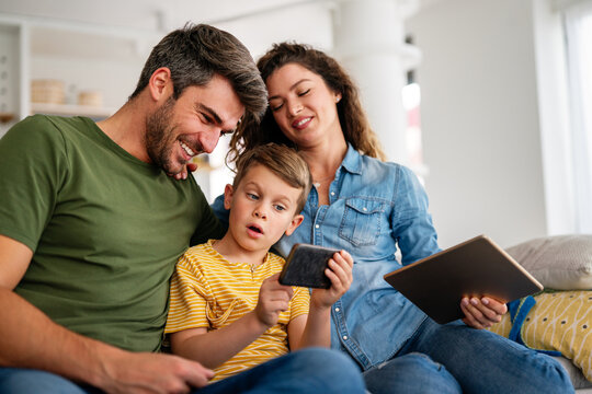 Happy family and kid having fun with smartphone, digital gadget at home. People, technology