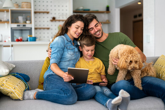 Joyful Caucasian family spending time together with digital devices and dog at home.