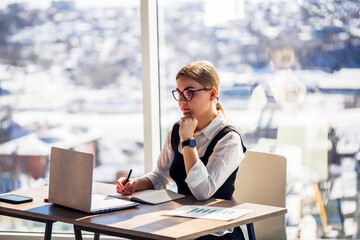 In a modern office, a skilled woman diligently works at her stylish desk, inspired by the...